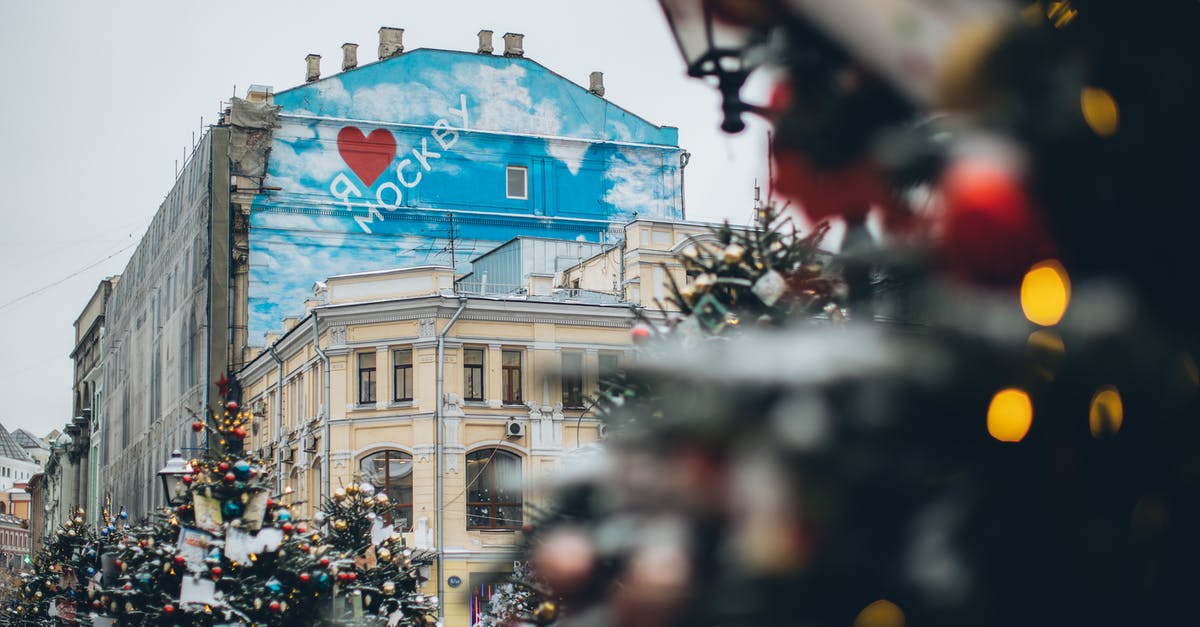 Can anyone recognise the location and uniforms in these pictures - Facade of old building with creative graffiti with inscription located on city square with Christmas trees decorated with ornaments and colorful baubles