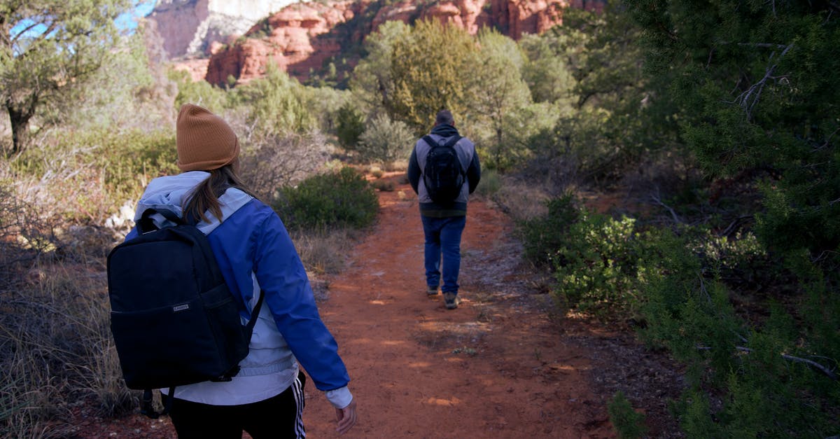 Can anyone recommend a good hiking trail in Scotland? - Man in Blue Jacket and Black Backpack Walking on Dirt Road