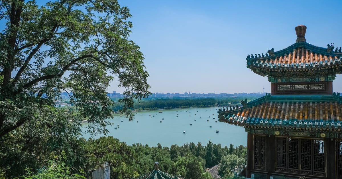 Can Chinese citizens currently leave China for tourism? - Multicolored Concrete Building  With A Lake View Showing The Distinct Architectural Design Of Ancient China