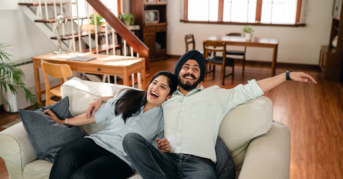 Can having a second wife affect my Australian visa processing/stay? - From above of cheerful young Indian couple in casual wear laughing and hugging each other while relaxing on cozy sofa in contemporary living room