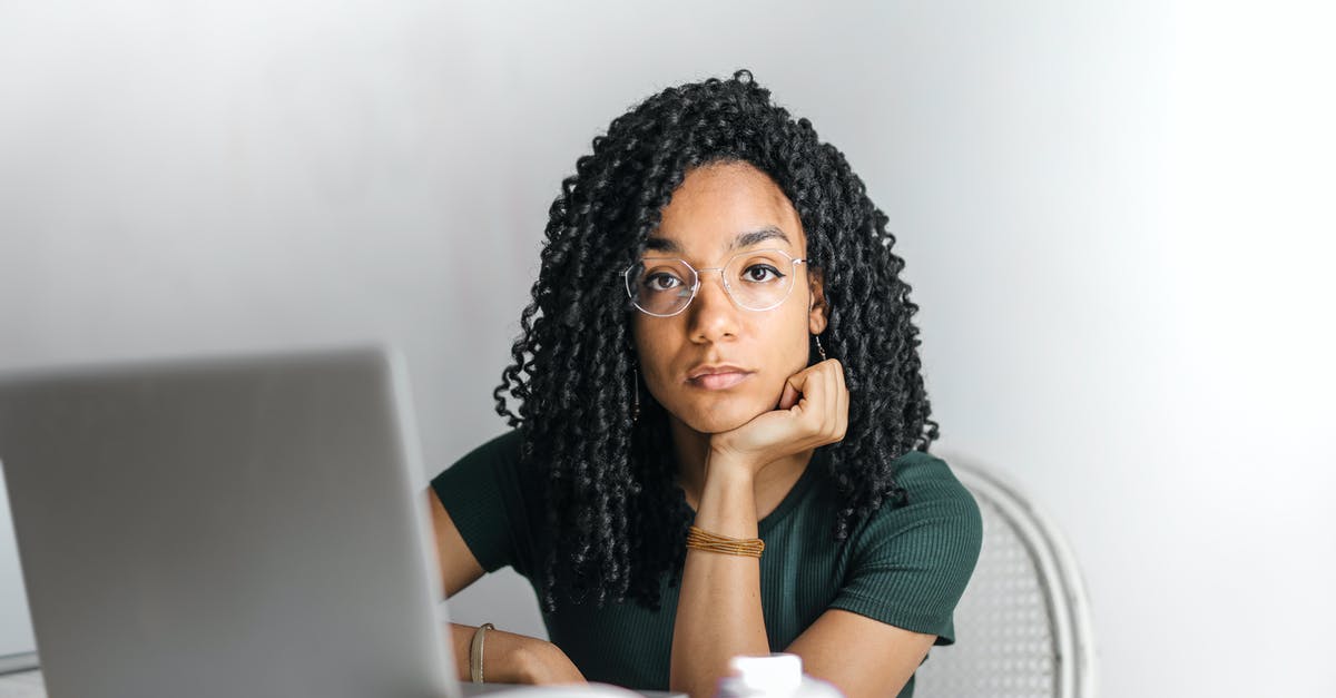 Can I add checked bags after online check-in (American) - Serious ethnic young woman using laptop at home