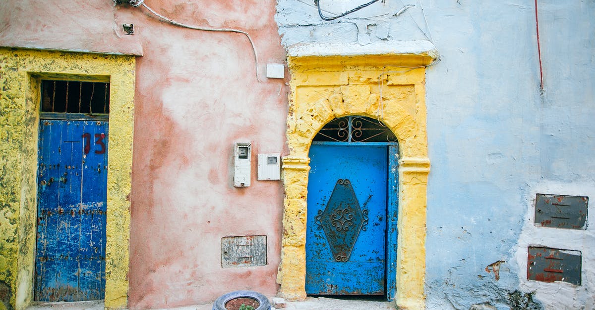 Can I be refused entry due to my place of birth? - Exterior of aged house with cement walls and threadbare doors on pavement street