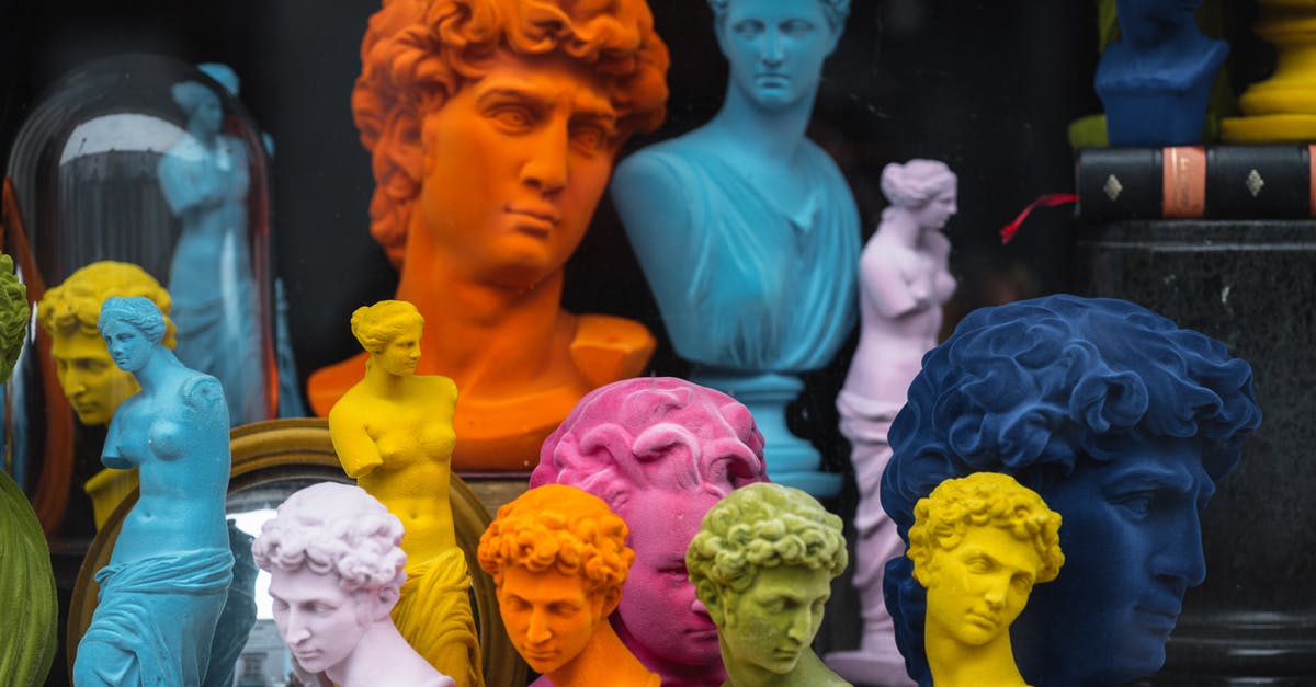 Can I book a different accommodation after receiving my US visa? - Multicolored head sculptures of David near bright statuettes placed in store with abundance of souvenirs and black pillar with book