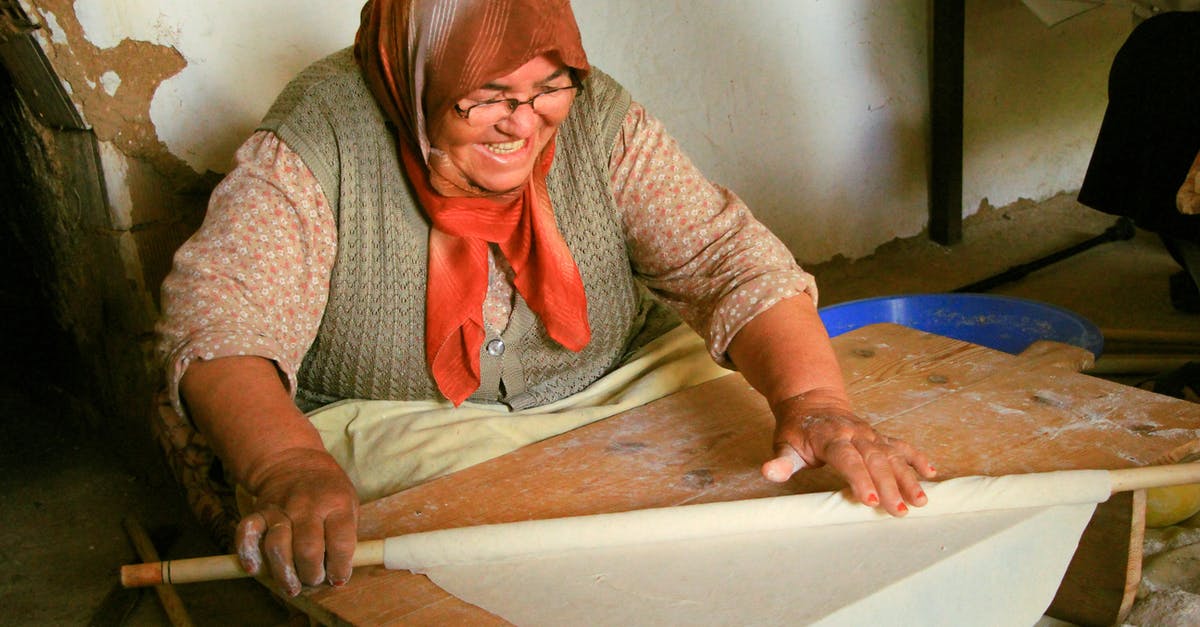 Can I bring a wooden dough rolling stick onto the plane(carry-on)? - Woman Wearing a Headscarf Rolling a Dough