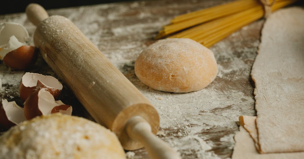 Can I bring a wooden dough rolling stick onto the plane(carry-on)? - Uncooked balls of dough near rolling pin placed on wooden table sprinkled with flour with eggshell and raw spaghetti in kitchen