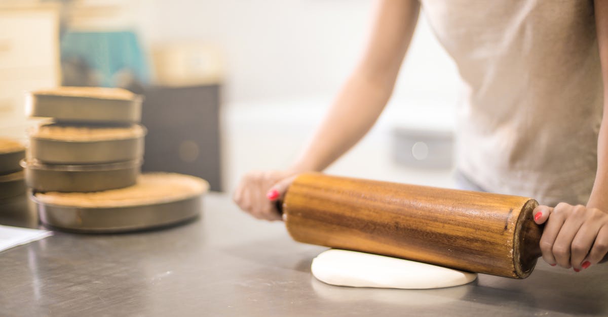 Can I bring a wooden dough rolling stick onto the plane(carry-on)? - Person in White T-shirt Rolling a Pin in Dough