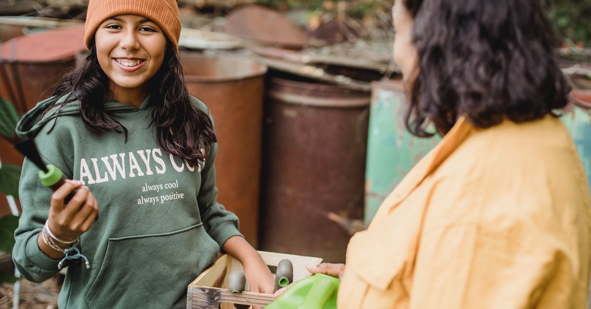 Can I bring an 18x6x6 inch Metal Box on Flight? - Happy ethnic girl with gardening tool and box looking at camera near crop unrecognizable mother on farm