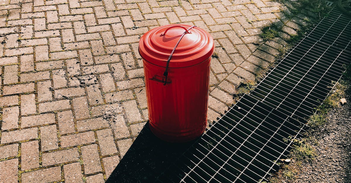 Can I bring an empty eggshell into Australia? - High angle of red metal trash can placed on pavement near sewer grates in city street in sunny summer day