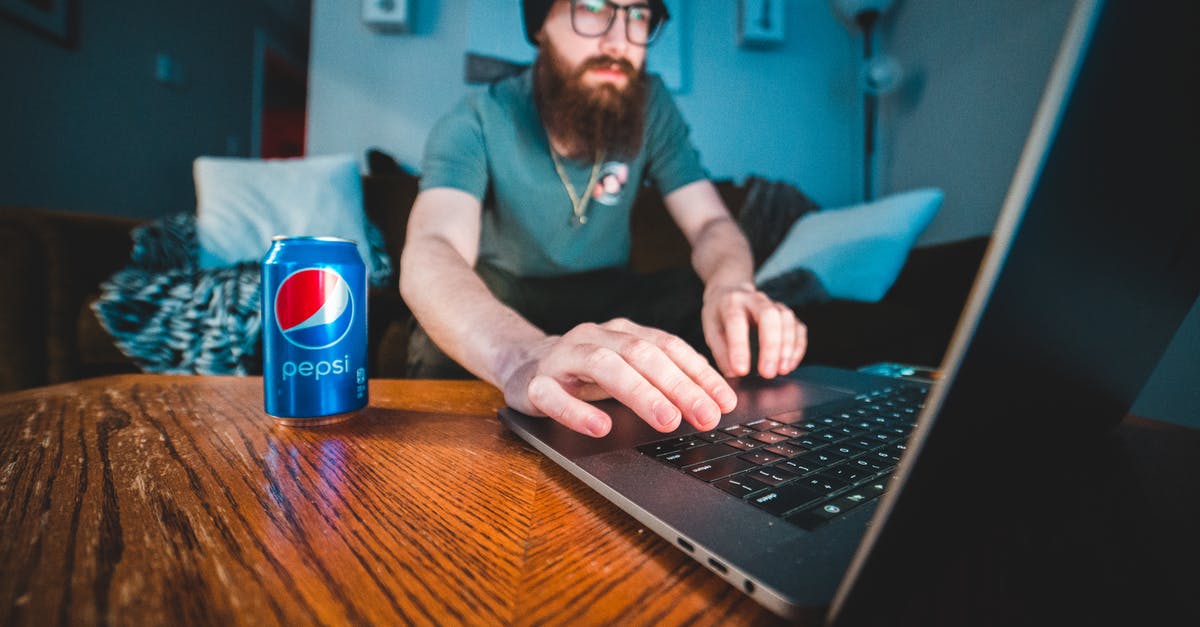 Can I bring caustic soda (sodium hydroxide) in my checked-in luggage? - Man in Blue Polo Shirt Using Black Laptop Computer