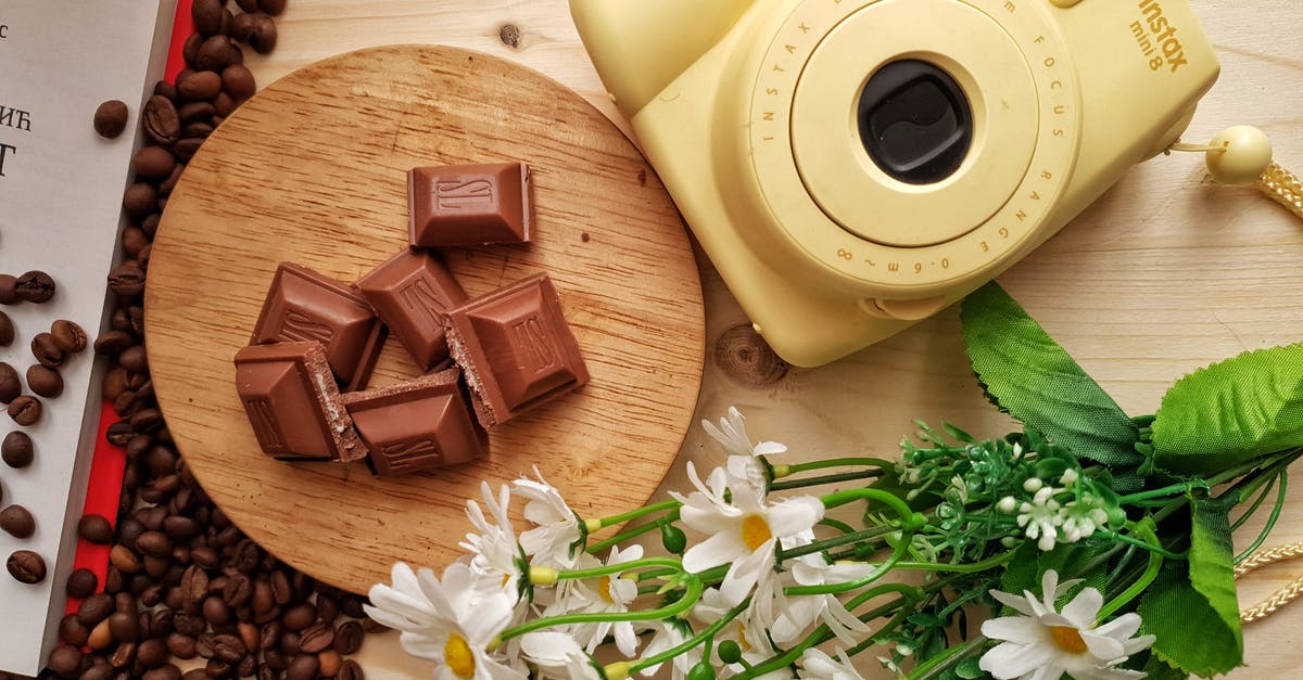 Can I bring chocolate from Belgium to Georgia? - Top view of delicious pieces of milk chocolate bar with filling on wooden board near heap of aromatic coffee beans and instant camera with artificial chamomiles on table