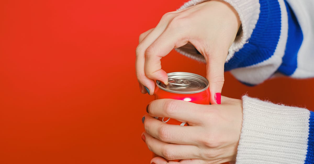 Can I bring compressed air cans in the airport? - Person Holding Can With Blue and White Knit Sweater