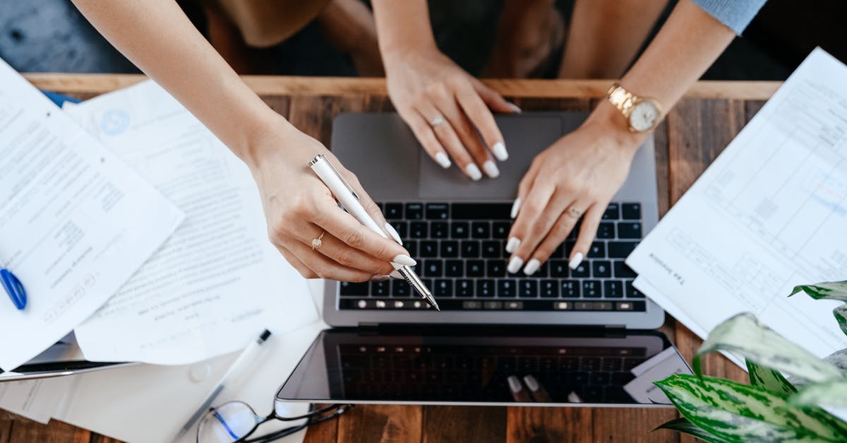 Can I bring my desktop parts with me to Canada? - Top view of anonymous women browsing modern netbook while sitting at wooden desk with stack and documents during work in office