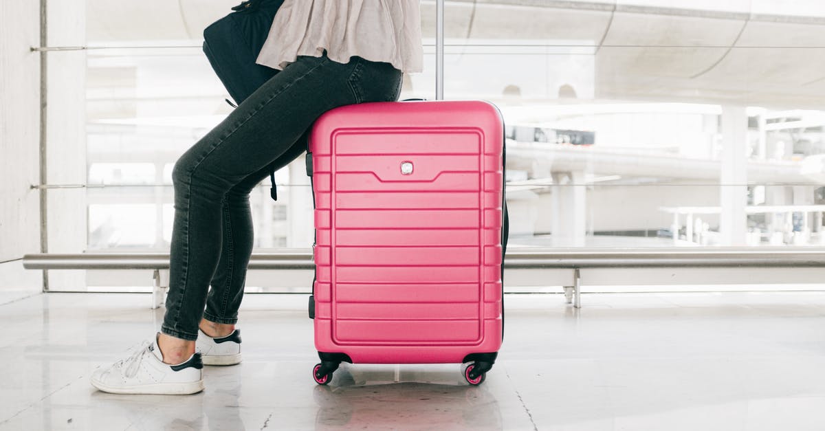 Can I buy a suitcase at LAX airport (Los Angeles)? - Woman In White Top And Denim Jeans Sitting  On Red Luggage Bag