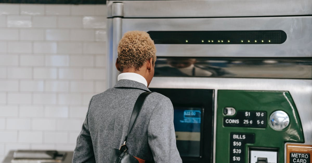 Can I buy two one way tickets for a trip? - Back view of unrecognizable ethnic female manager with short dyed hair in elegant suit buying ticket with electronic machine in subway station