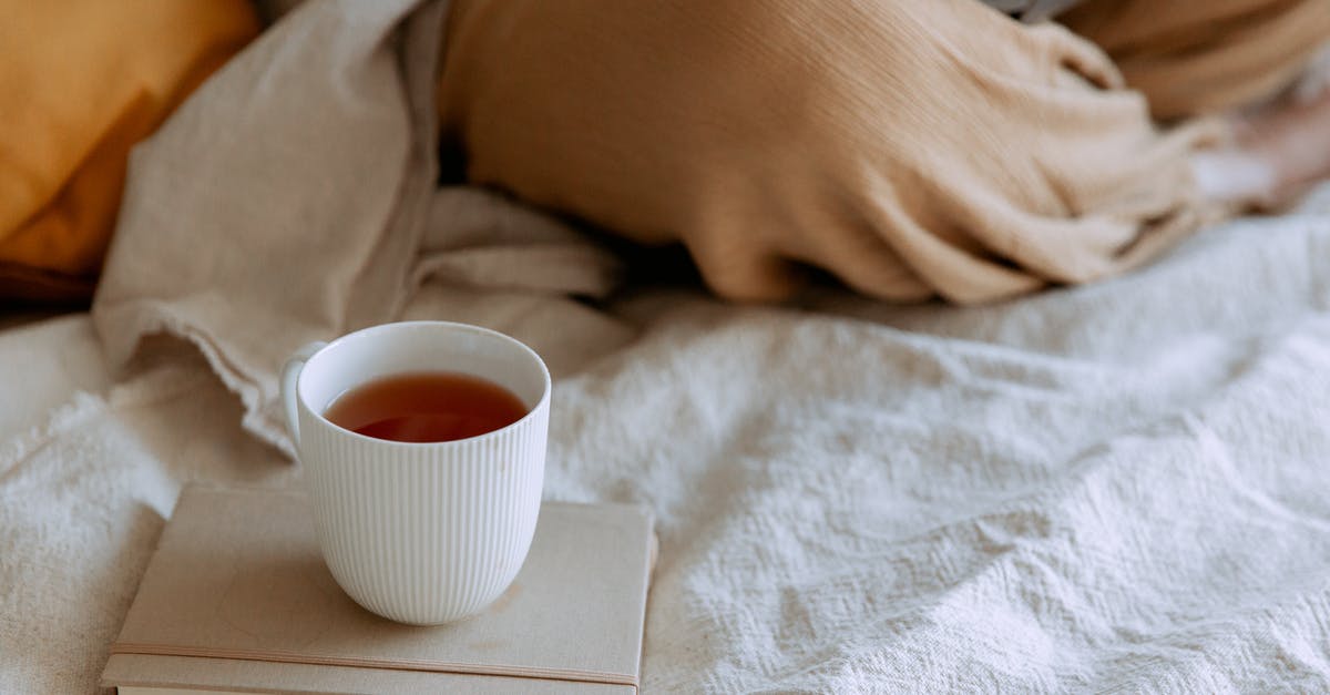 Can I carry used computer parts from India to Germany - From above of tea placed on notepad near freelancer sitting with crossed legs using netbook on bed at home