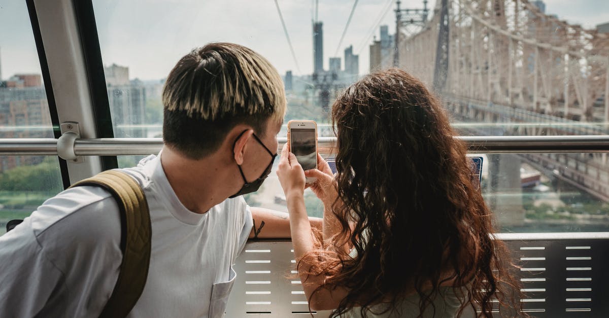 Can I change my travel destination for ESTA during COVID? - Young couple in protective mask taking photo on smartphone while riding together on cableway during vacation