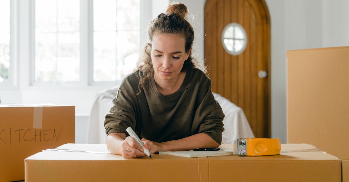 Can I check a cardboard box on a Qantas flight? - Concentrated young lady preparing carton boxes for relocation