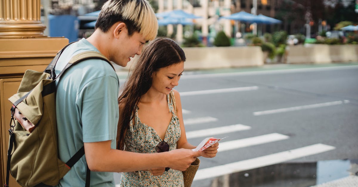 Can I check in all the way through? - Traveling couple standing on sidewalk with map