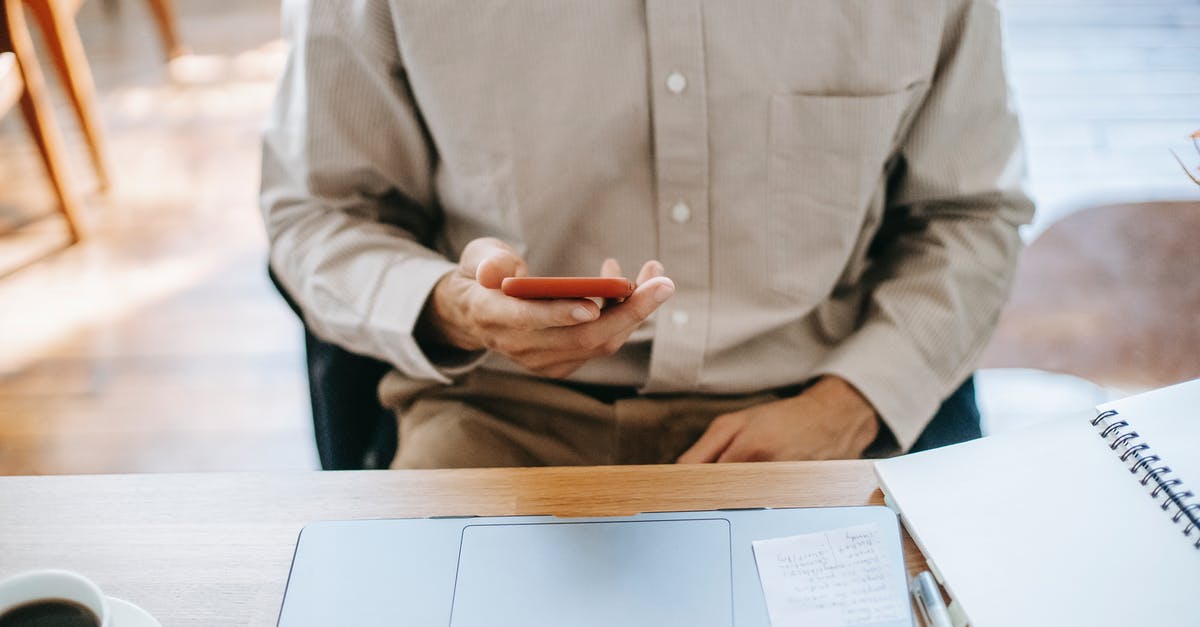 Can I check-in online for self transfer flights? - Crop unrecognizable man in casual clothes working remotely on computer while sitting at wooden table and checking notifications on phone near notebook and cup of coffee in light room