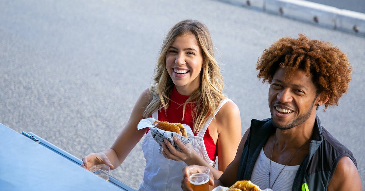 Can I eat a beef burger in India? - Delighted multiethnic couple with drinks and food on street