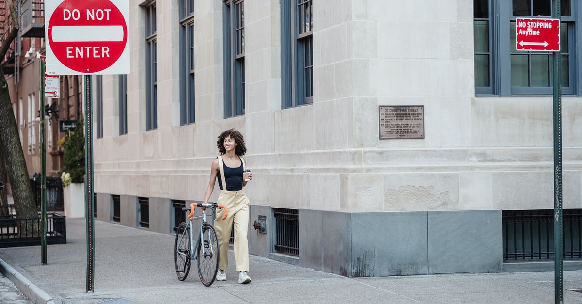 Can I enter Colombia on a one way ticket? - Contemplative ethnic woman with coffee and bike walking on pavement