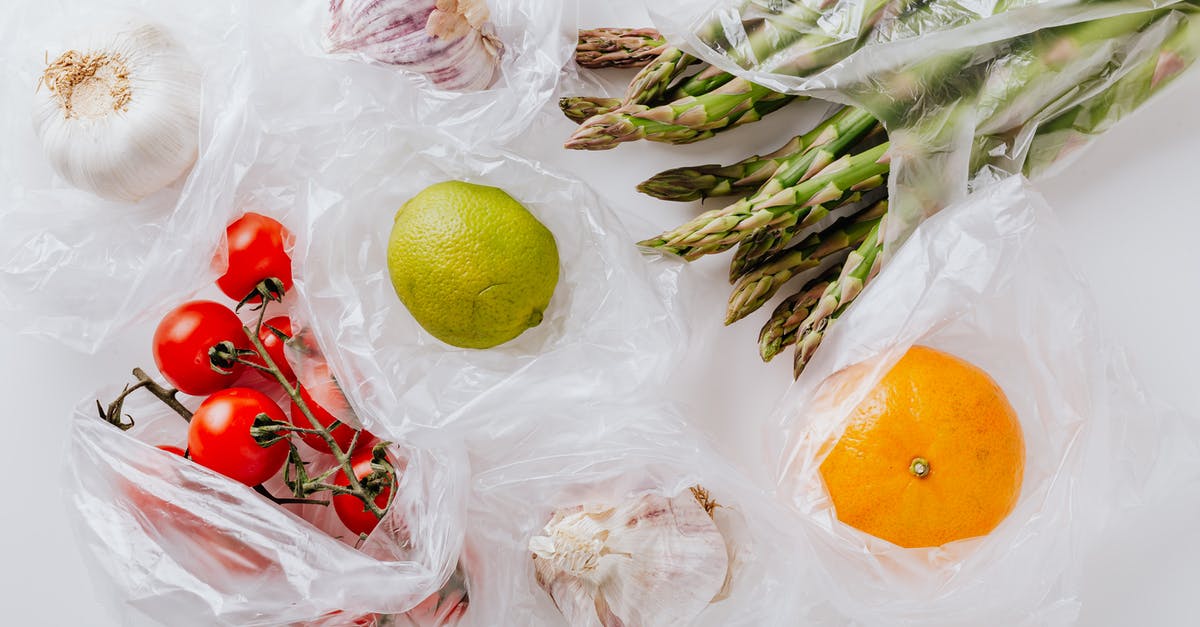 Can I fly with white powder in a transparent bag? - From above of bunch of tomatoes with raw asparagus put into transparent plastic bags on white table near citrus fruits and garlic bulbs