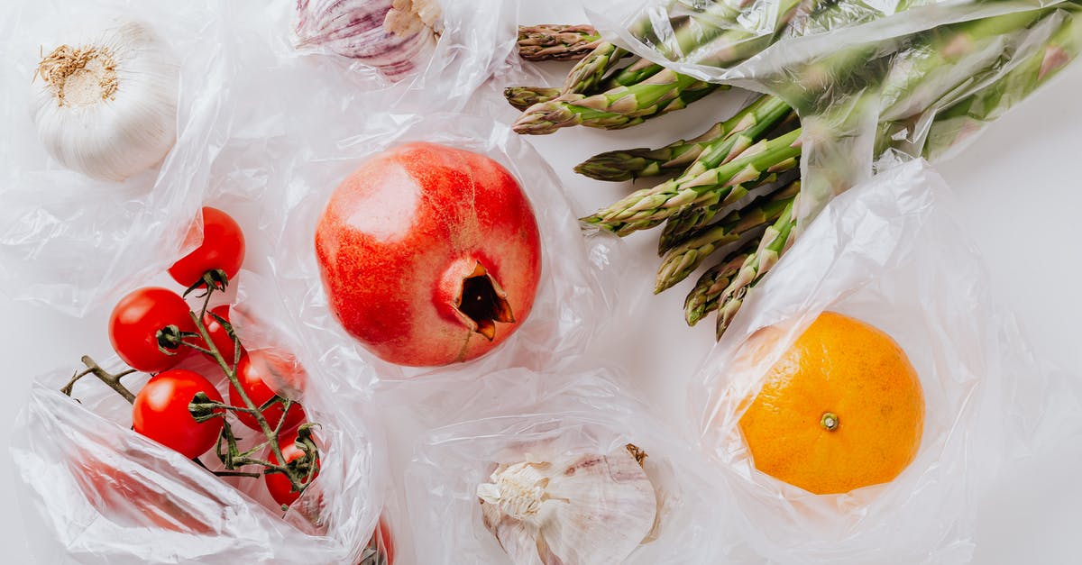 Can I fly with white powder in a transparent bag? - Top view of pomegranate in center surrounded by bundle of raw asparagus with orange and bunch of tomatoes put near heads of garlic in plastic bags on white surface