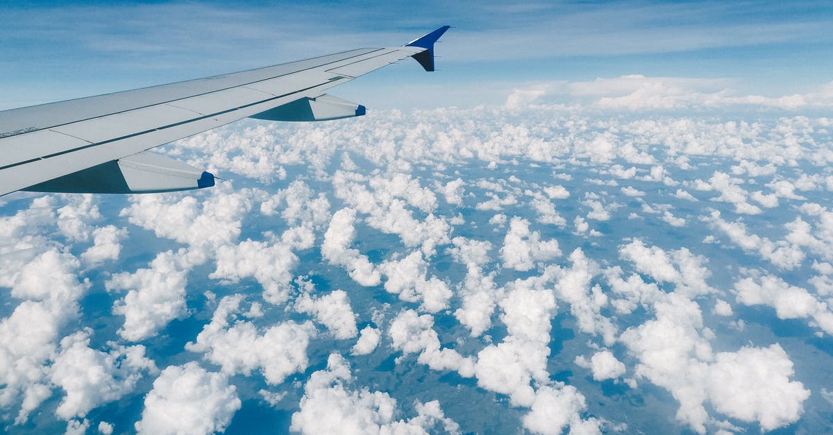 Can I get free accommodation when traveling on Jet Airways with a long layover? - Aerial view of modern metal airplane wing in blue sky over fluffy clouds