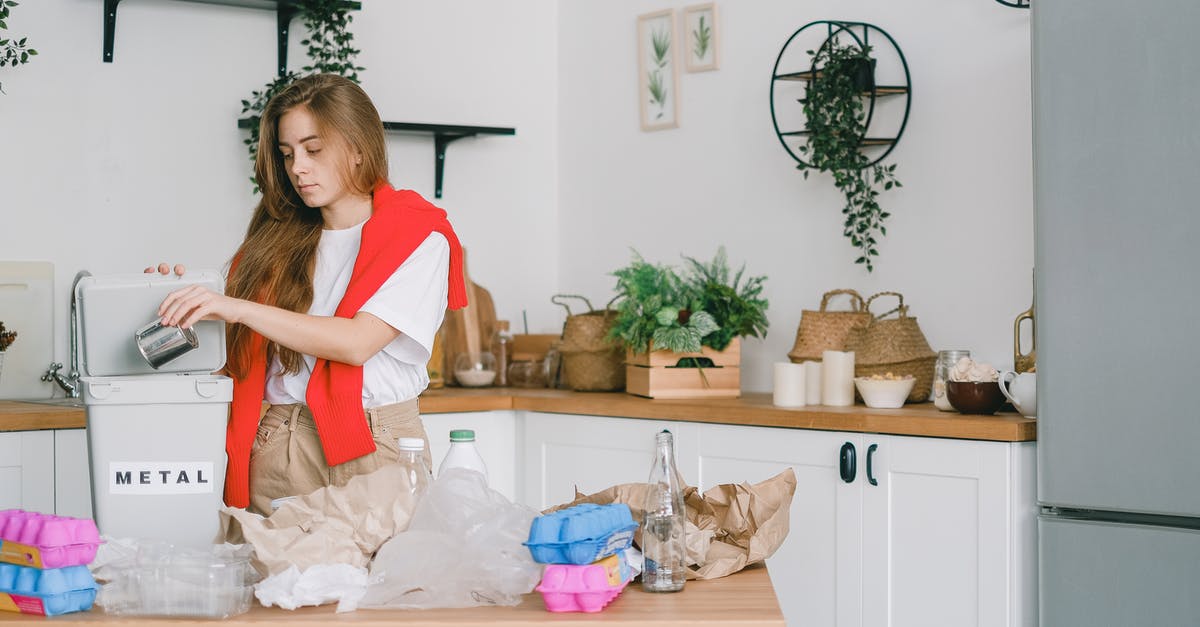 Can I go through transfers with separate tickets/airlines? - Young responsible female standing in kitchen and putting tin can into bucket while sorting trash