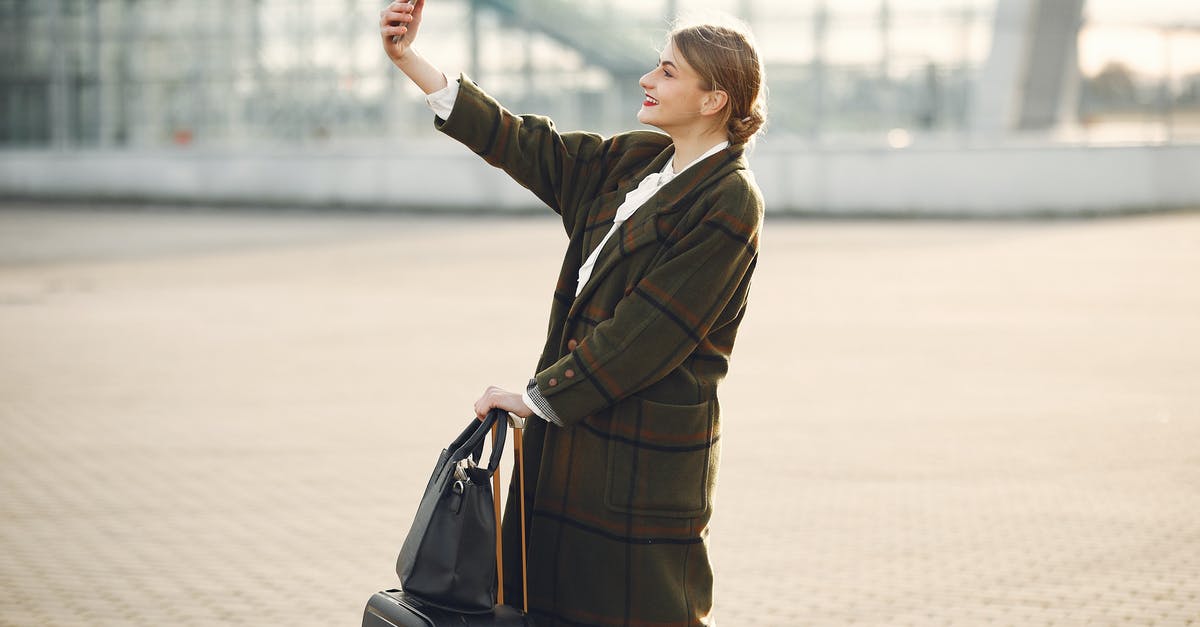 Can I make a short trip to Northern Ireland? - Stylish young woman with luggage taking selfie outside modern glass building