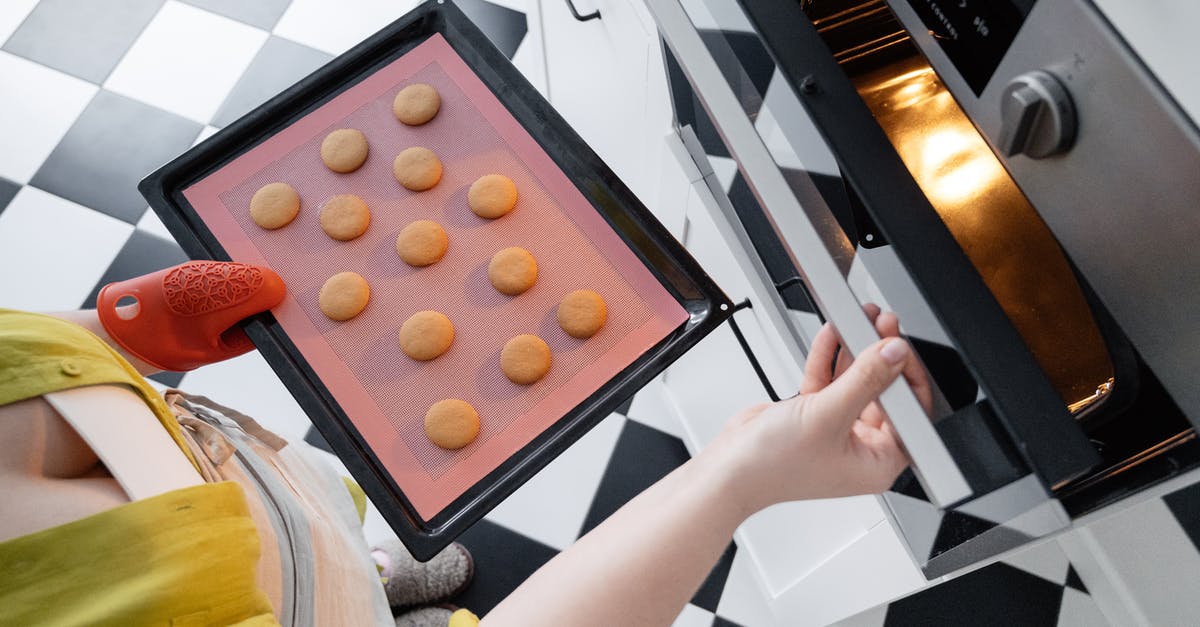 Can I put food in my hold luggage for flying? - From above of crop unrecognizable female opening oven and putting baking pan with uncooked cookies inside oven in kitchen