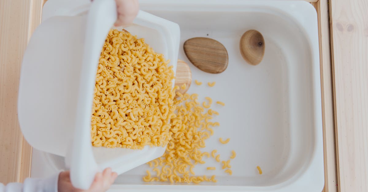 Can I put food in my hold luggage for flying? - Unrecognizable crop kid adding raw pasta to white container