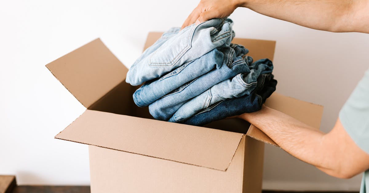 Can I put Kensington lock in my hand luggage? - Crop unrecognizable male putting staked jeans into opened cardboard container before renovation while standing against white wall in daylight