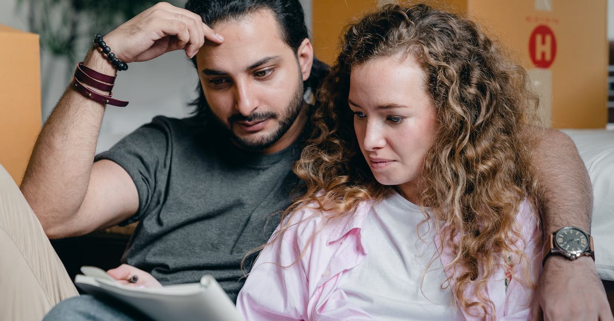 Can I remove an "attention" sticky note in my passport? - Focused male and female in casual wear sitting near boxes and looking through notebook thoughtfully while moving house