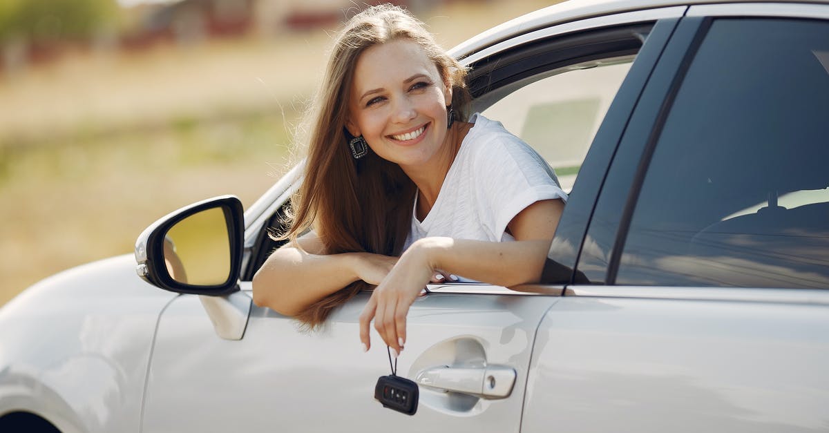 Can I rent a car in Berlin and drive to Krakow? - Happy woman with car key in modern automobile during car trip