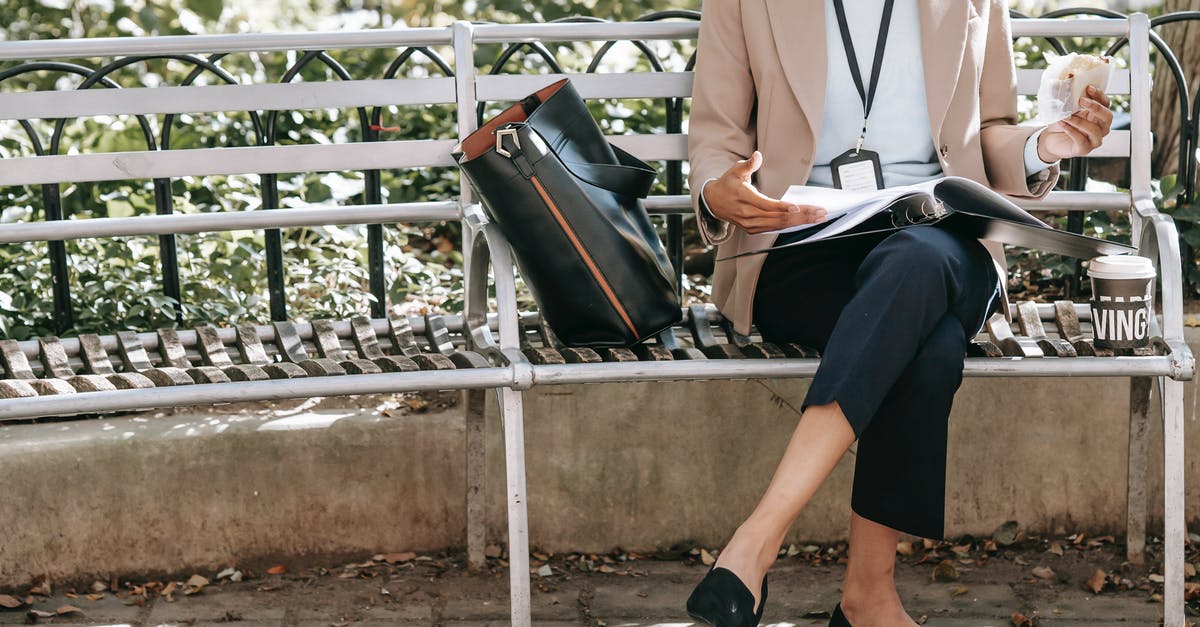 Can I safely eat whatever goes through the x-ray machine? - Crop unrecognizable female student reading papers in folder while eating sandwich on bench in park