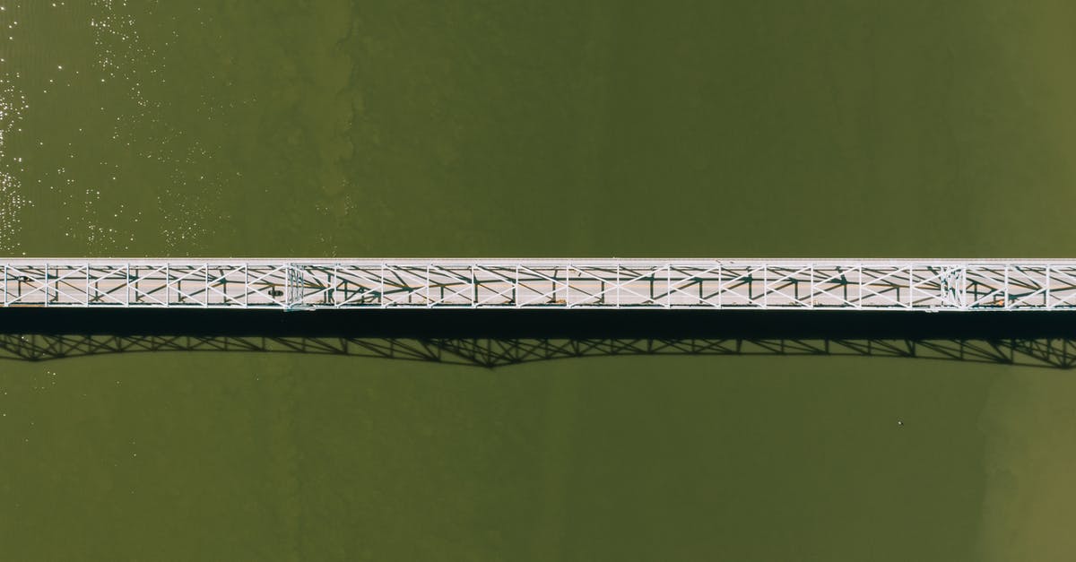 Can I stay in Schengen area after my visa still valid but breach the condition - Aerial top view of modern motor bridge crossing vast rippling river on sunny day