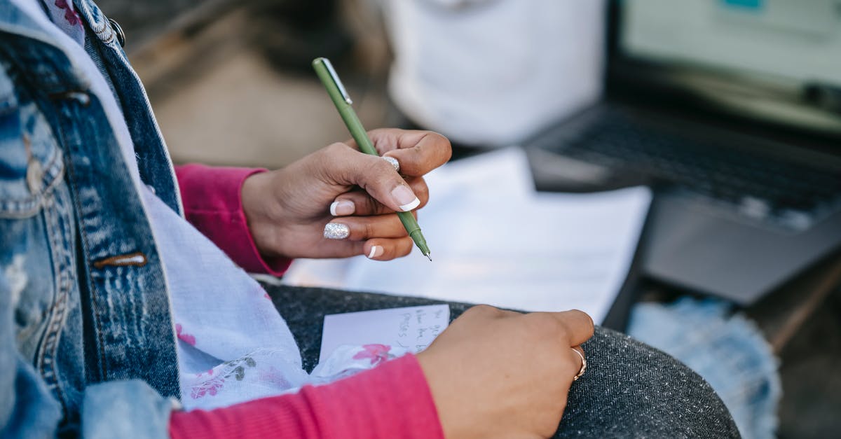 Can I submit Job offer letter as proof of employment? - Crop anonymous female student writing notes on paper placed on knees while sitting on bench with laptop in city street