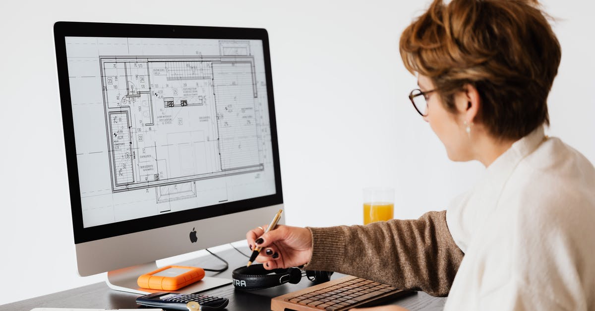 Can I take a 24" computer monitor on board? - Side view of anonymous female employee in casual clothes and eyeglasses writing out information from computer while working at table in modern light office