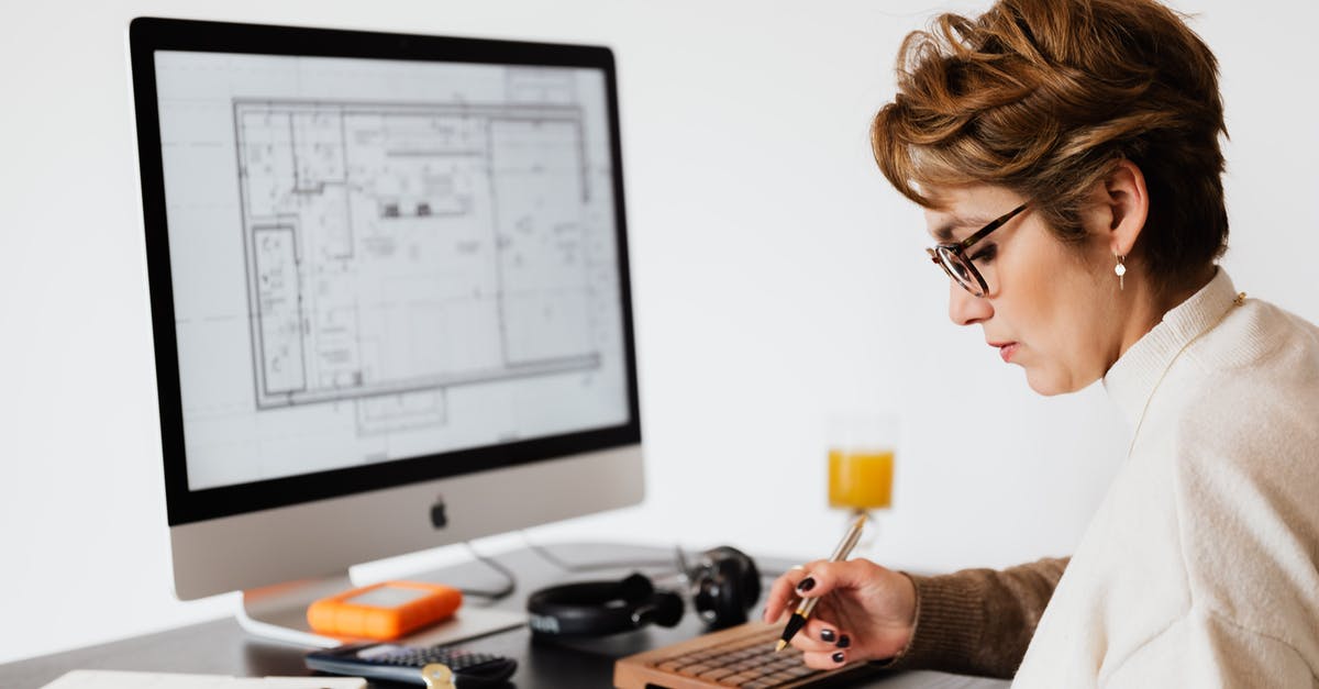 Can I take a 24" computer monitor on board? - Focused woman editing paper documents during work at desk with computer