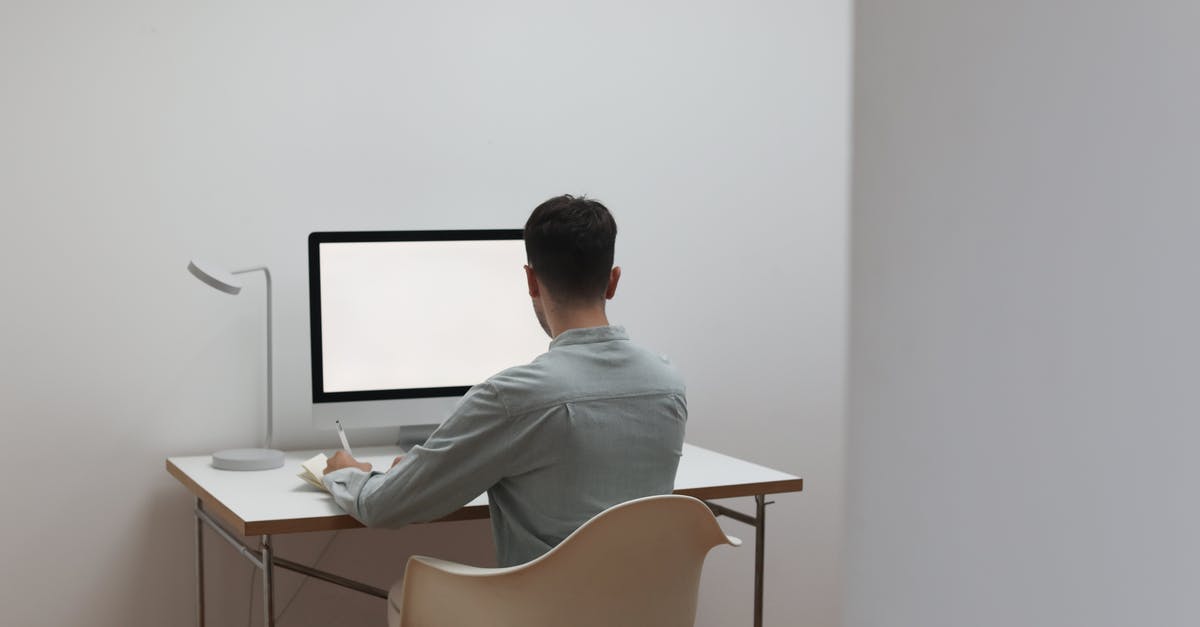 Can I take a 24" computer monitor on board? - Unrecognizable man working on computer at home