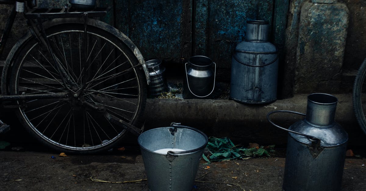 Can I take a boxed bicycle on a German train? - Tin vessels and metal bucket with milk placed near bike leaned on shabby rusty wall