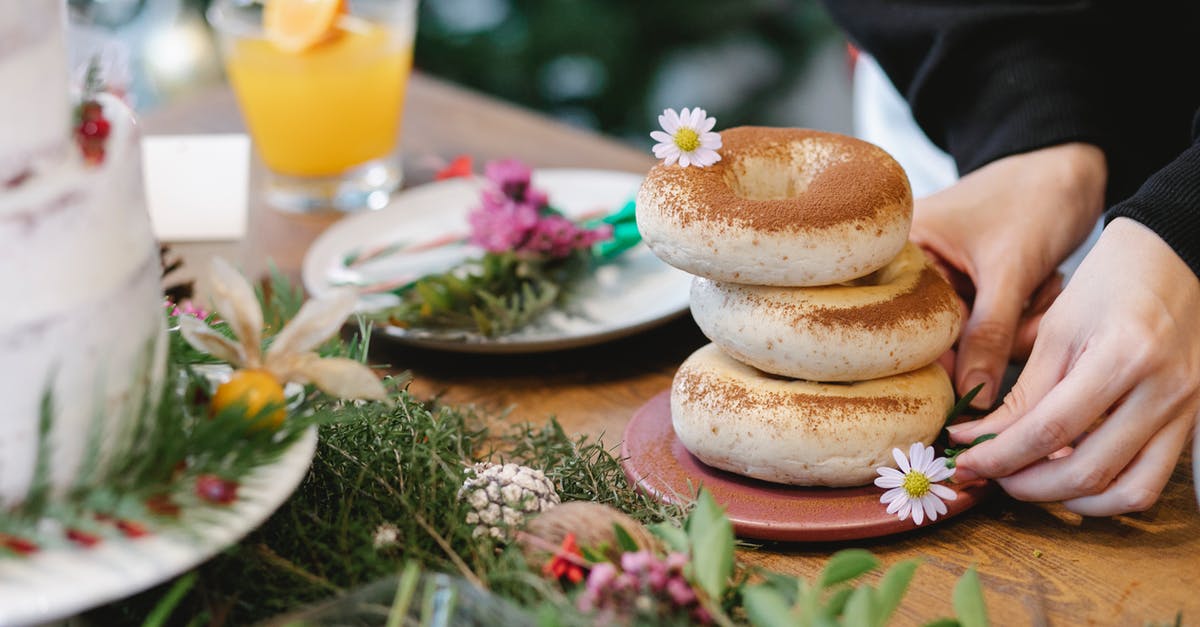 Can I take a home baked christmas cake into Australia? - Faceless cook with pile of bagels decorated with cinnamon powder and blossoming chamomiles on plate during New Year holiday indoors