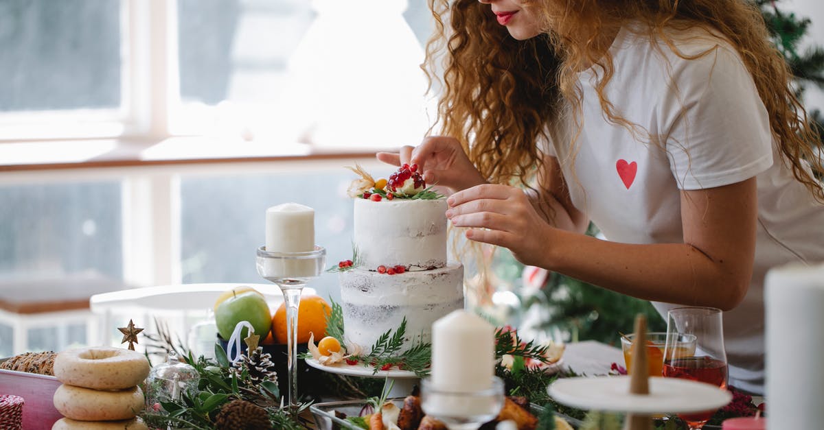 Can I take a home baked christmas cake into Australia? - Crop serious female adding berries on top of two tier cake for festive dinner for New Year holiday