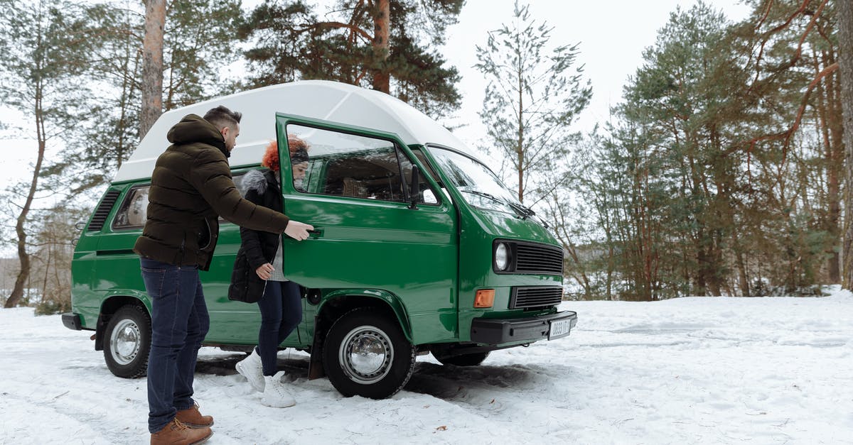 Can I take a scheduled bus on an ice road? - Man in Green Jacket Standing Beside Green Car