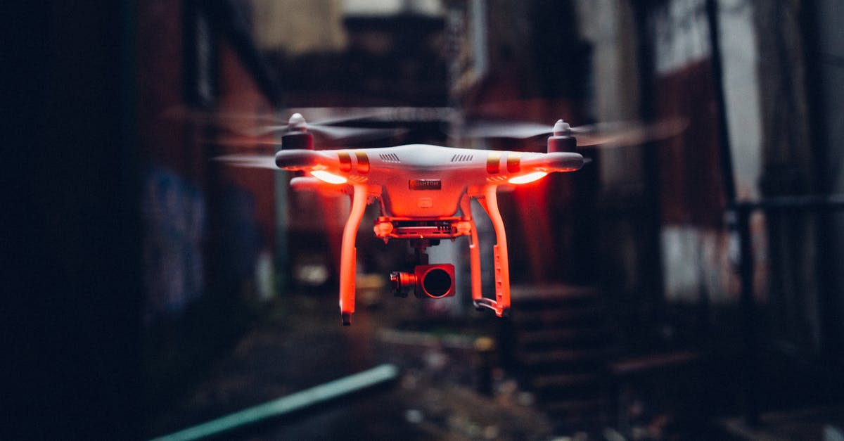 Can I take an electric fly swatter on board? - Red glowing modern drone flying in air on blurred background of gloomy industrial street