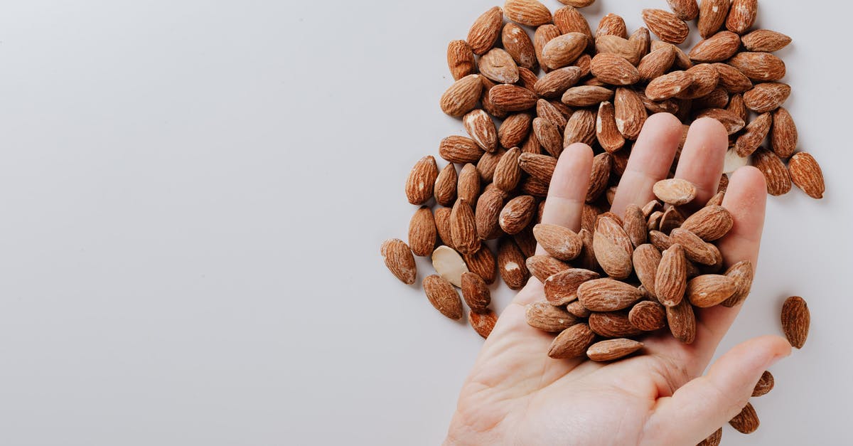 Can I take camping food in hand luggage? - From above of anonymous male taking tasty organic almonds from pile of nuts placed on white background isolated illustrating healthy food concept