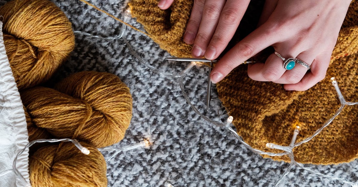 Can I take knitting needles on an international flight? - Photo Of Person Holding Brown Yarn Roll