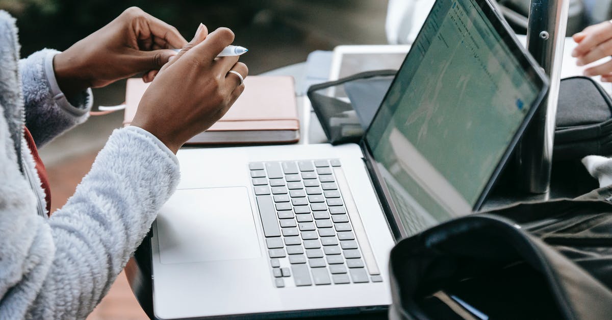 Can I take my 15.6" laptop bag with me on my Ryanair flight? - From above of crop anonymous multiethnic female students working together on assignment using laptop ant taking notes at round table in campus