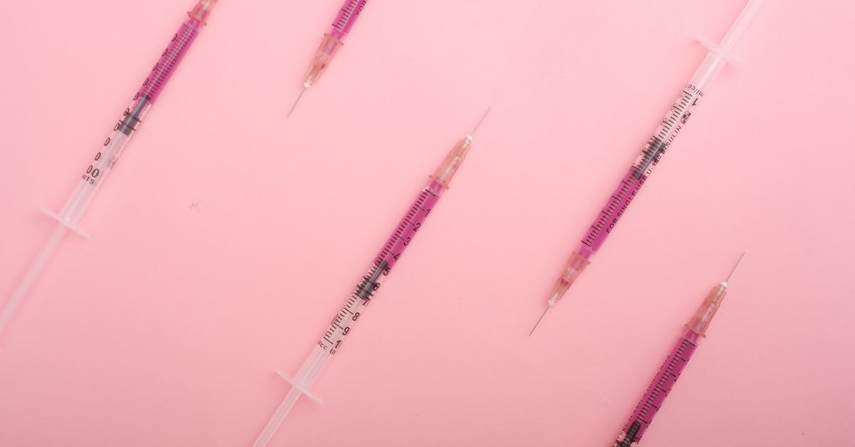 Can I take my liquid medication on a plane? - Top view set of syringes with purple colored liquid medicine arranged on pink background as background